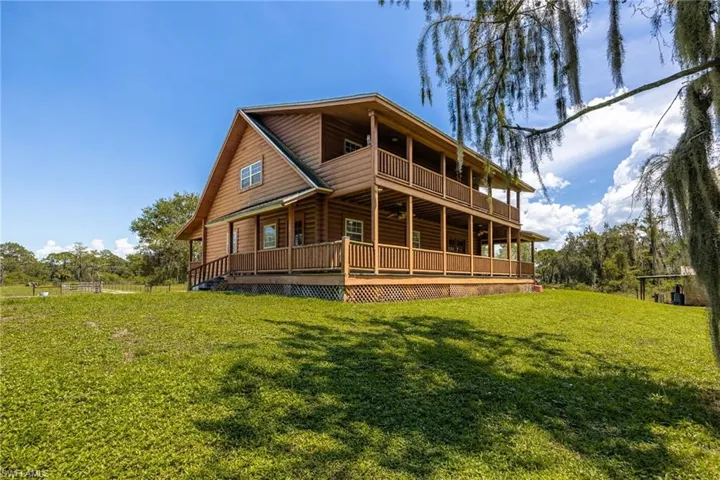 Rear view of property featuring covered porch, a yard, and faux log siding