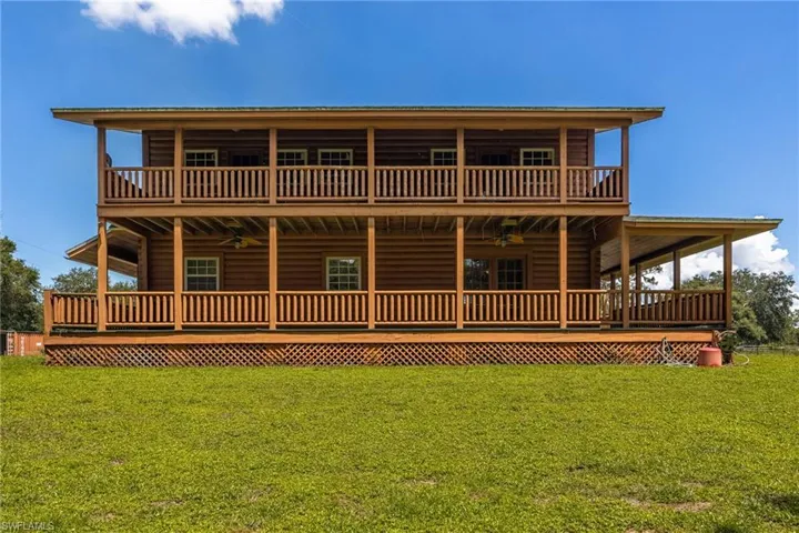 View of front of house with ceiling fan, faux log siding, a large porch, and a front yard
