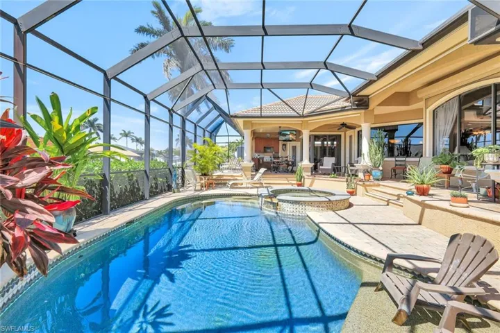 View of pool with a patio, glass enclosure, a pool with connected hot tub, a sunroom, and outdoor dining space