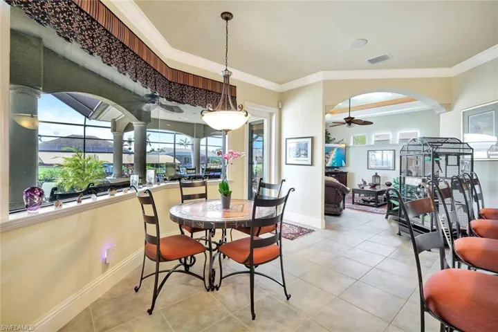 Dining space with crown molding, tile patterned flooring, a sunroom, plenty of natural light, and a ceiling fan