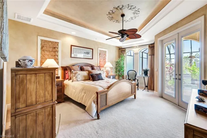 Bedroom with a raised ceiling, access to exterior, light carpet, and french doors