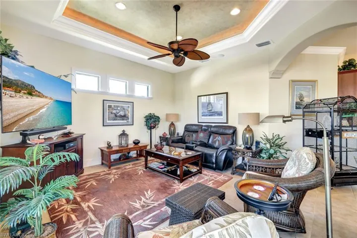 Living area featuring a ceiling fan, a raised ceiling, recessed lighting, and crown molding
