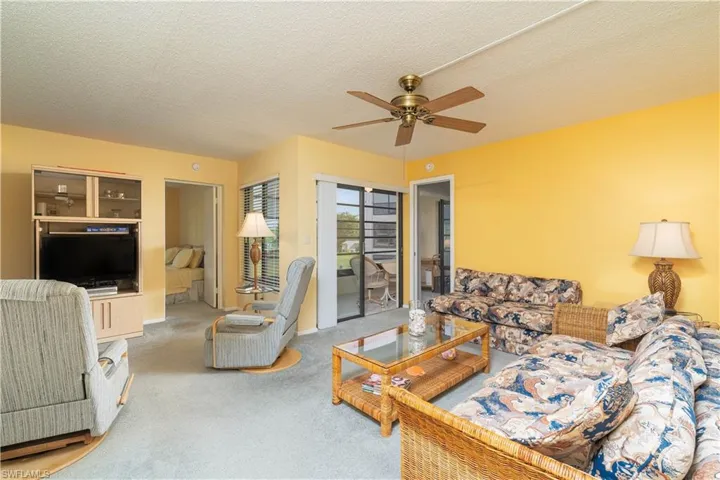 Carpeted living room featuring a textured ceiling and ceiling fan