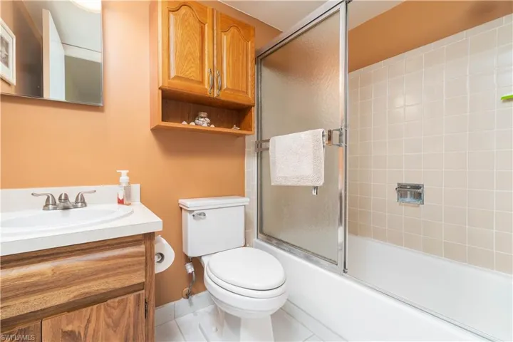 Full bathroom featuring toilet, vanity, and shower / bath combination with glass door