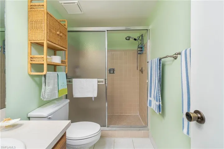 Bathroom featuring toilet, tile patterned flooring, an enclosed shower, and vanity