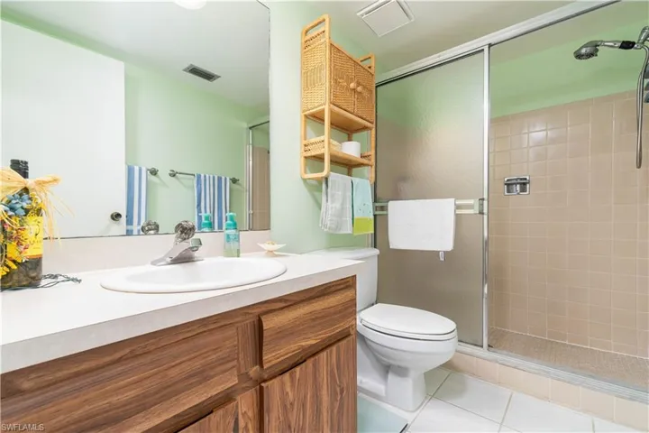 Bathroom with vanity, toilet, tile patterned floors, and a shower with shower door