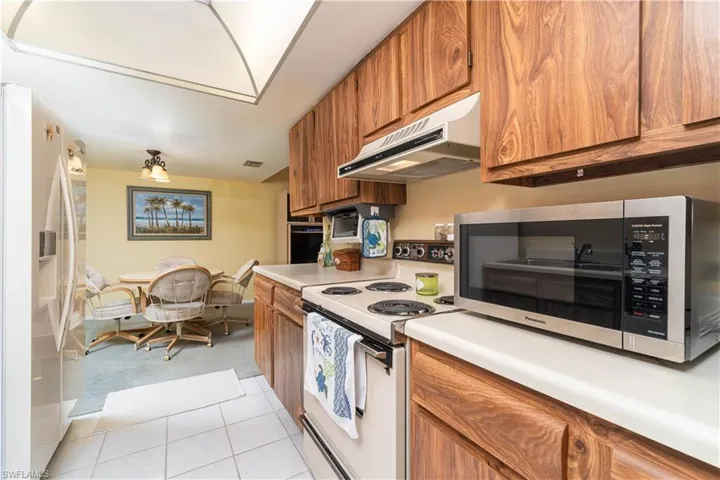 Kitchen featuring fridge with ice dispenser, oven, light tile patterned flooring, and electric stove