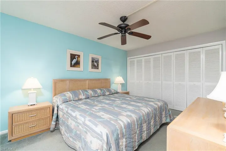 Carpeted bedroom with a textured ceiling, ceiling fan, and a closet