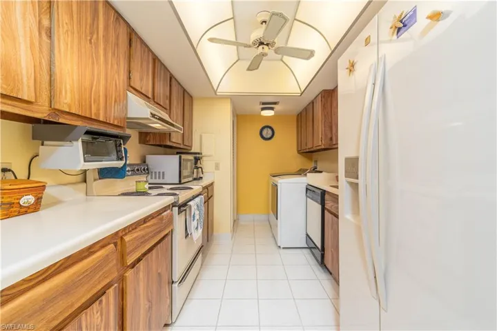 Kitchen featuring stainless steel appliances, washer / clothes dryer, light tile patterned flooring, and ceiling fan