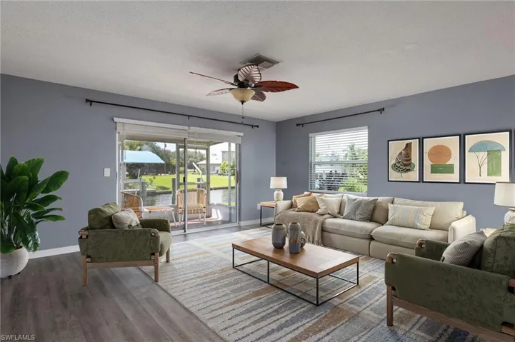 Living room featuring a ceiling fan, wood finished floors, a textured ceiling, and a water view