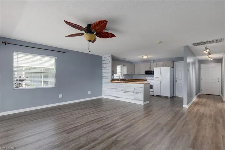 Kitchen featuring open floor plan, white appliances, a peninsula, a ceiling fan, and plenty of natural light