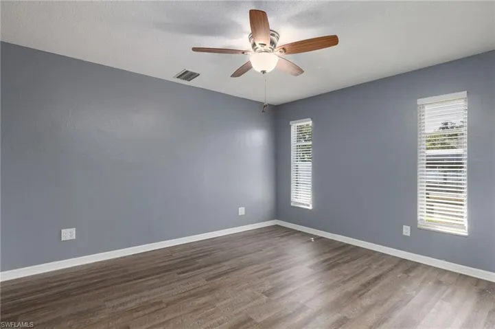 Unfurnished room featuring ceiling fan, dark wood-type flooring, and a textured ceiling