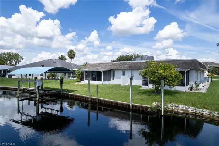 Dock area featuring a water view, a sunroom, a yard, and boat lift