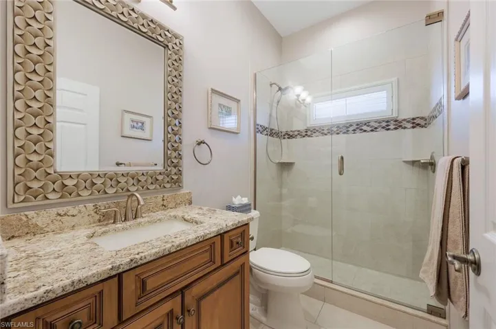 Bathroom featuring tile patterned flooring, a shower with door, vanity, and toilet