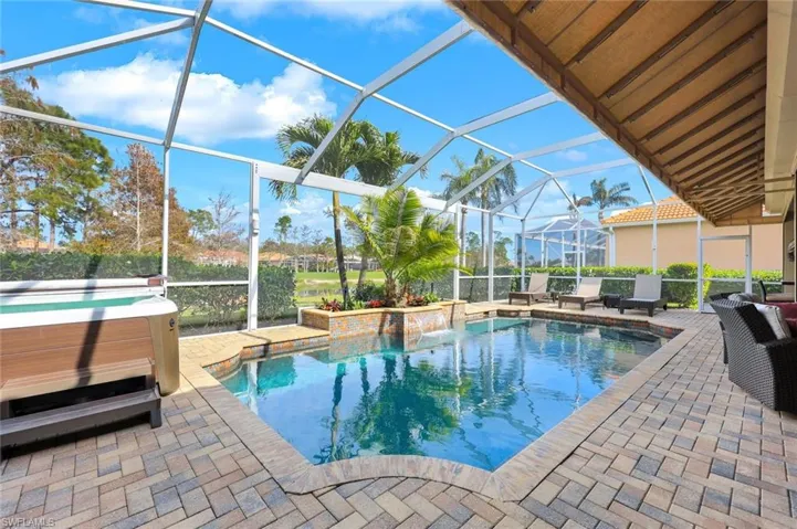 View of swimming pool with glass enclosure, a hot tub, and a patio area