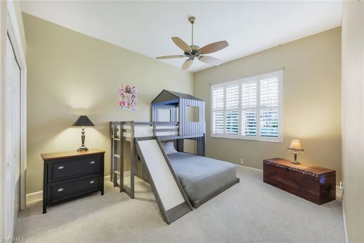 Bedroom with light colored carpet, a closet, and ceiling fan
