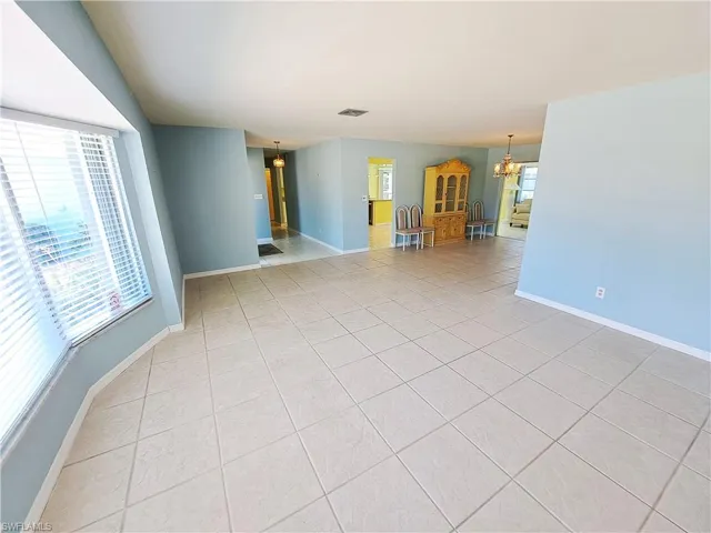 Empty room with light tile patterned floors and a chandelier