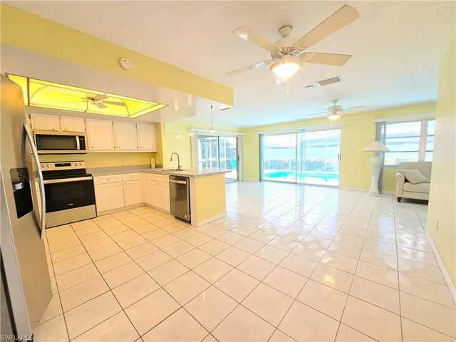 Kitchen with open floor plan, light tile patterned flooring, appliances with stainless steel finishes, and a peninsula