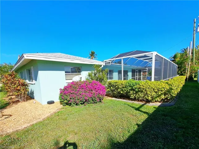 Rear view of property featuring stucco siding, a lawn, and a lanai