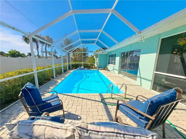 View of swimming pool featuring a patio and glass enclosure