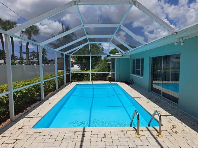 View of pool with a patio area and glass enclosure