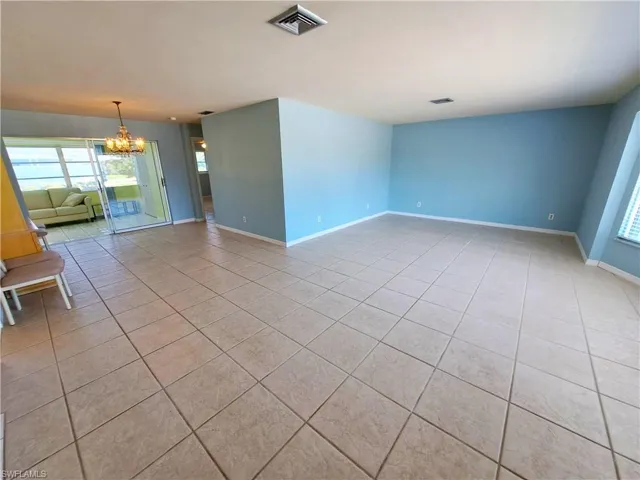 Unfurnished room featuring a chandelier and light tile patterned flooring
