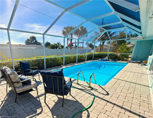 View of pool with a patio area and glass enclosure