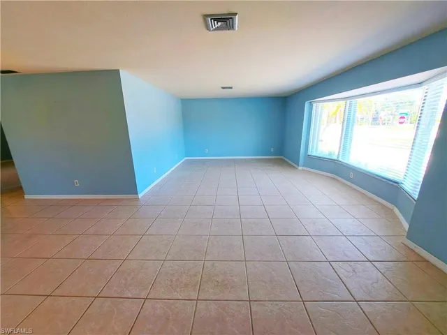 Empty room featuring light tile patterned floors and baseboards