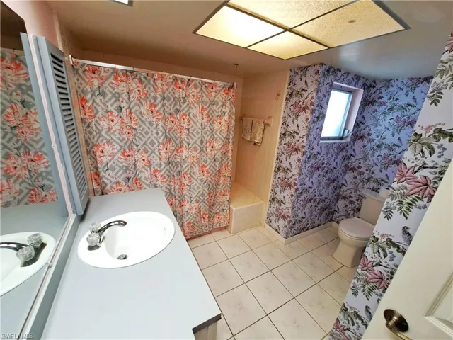 Bathroom with vanity, a shower with curtain, and wallpapered walls