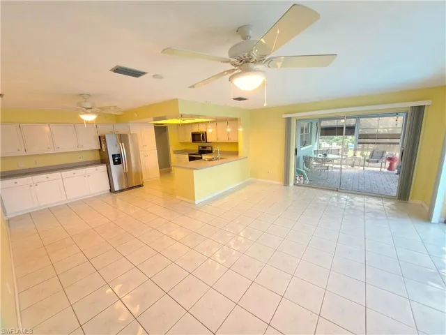 Kitchen featuring a peninsula, appliances with stainless steel finishes, light tile patterned flooring, open floor plan, and ceiling fan