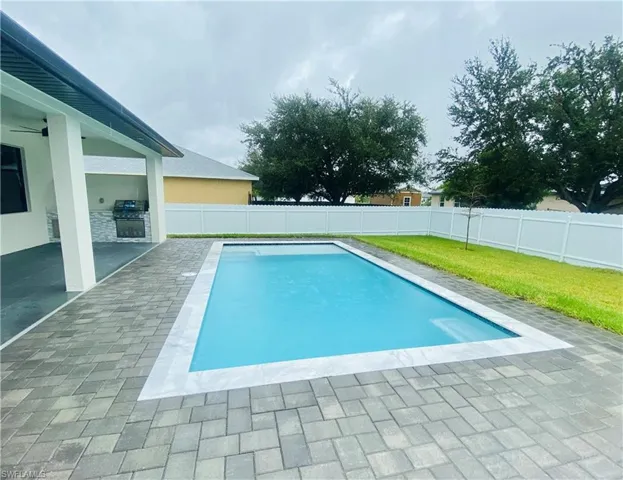 View of swimming pool with a grill, a lawn, and a patio area
