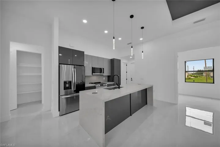 Kitchen featuring pendant lighting, an island with sink, sink, appliances with stainless steel finishes, and light tile patterned floors