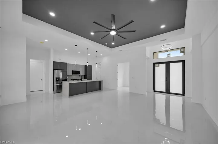 Kitchen with stainless steel appliances, a raised ceiling, light tile patterned floors, and ceiling fan