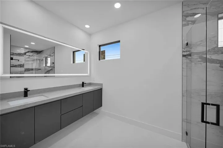 Bathroom featuring a shower with door and dual bowl vanity