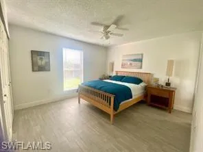 Bedroom with hardwood / wood-style floors, a textured ceiling, a closet, and ceiling fan
