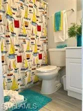 Bathroom featuring toilet, hardwood / wood-style floors, vanity, and a shower with shower curtain