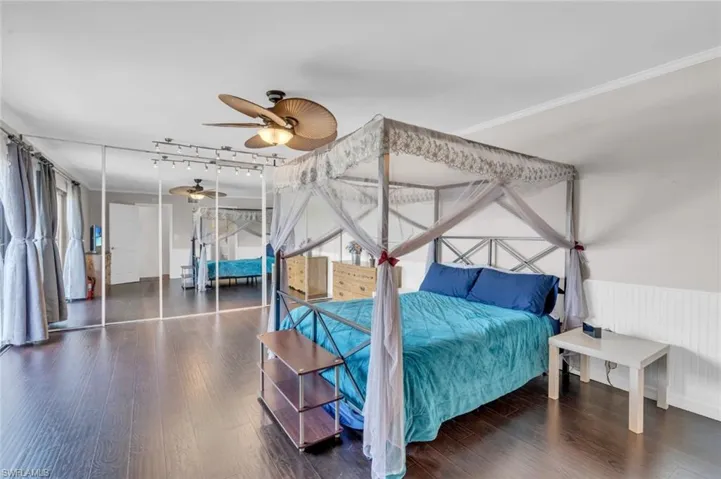 Bedroom featuring wood finished floors, crown molding, and rail lighting