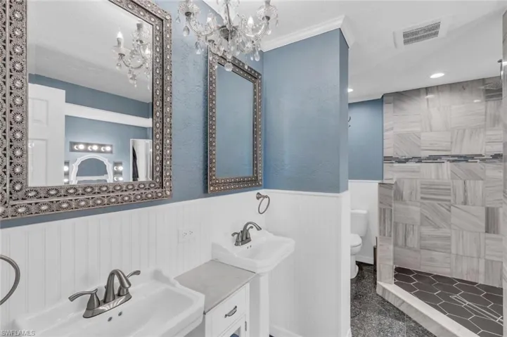 Bathroom with a wainscoted wall, a chandelier, a tile shower, recessed lighting, and granite floors