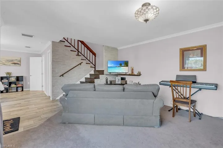Living area with ornamental molding and stairway