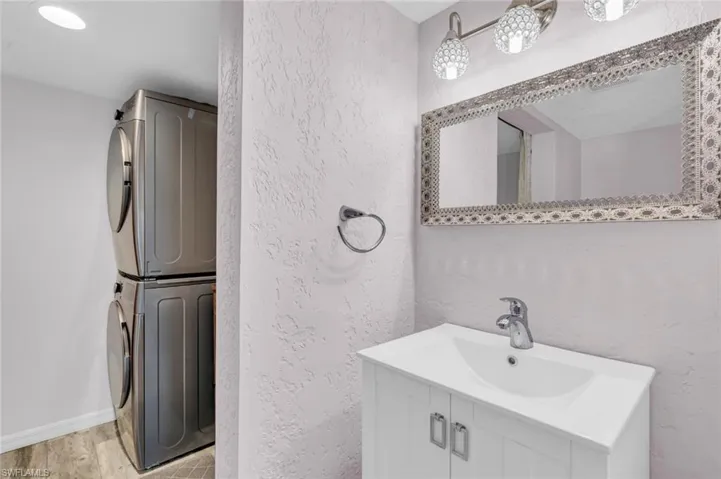 Bathroom featuring stacked washer / drying machine, vanity, and a textured wall