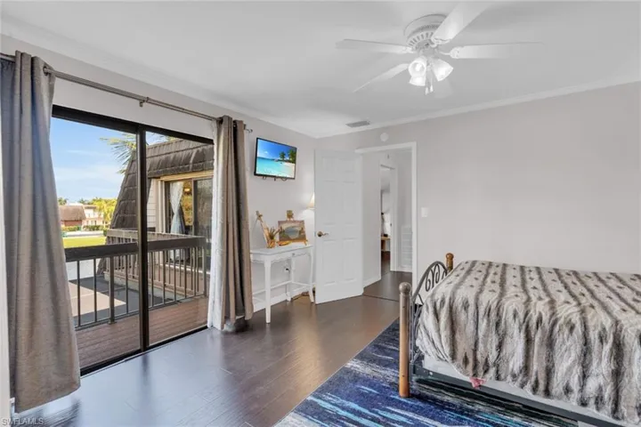 Bedroom featuring access to exterior, wood finished floors, ornamental molding, and ceiling fan