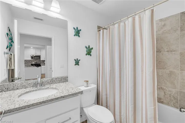 Full bathroom featuring vanity, toilet, and shower / bathtub combination with curtain