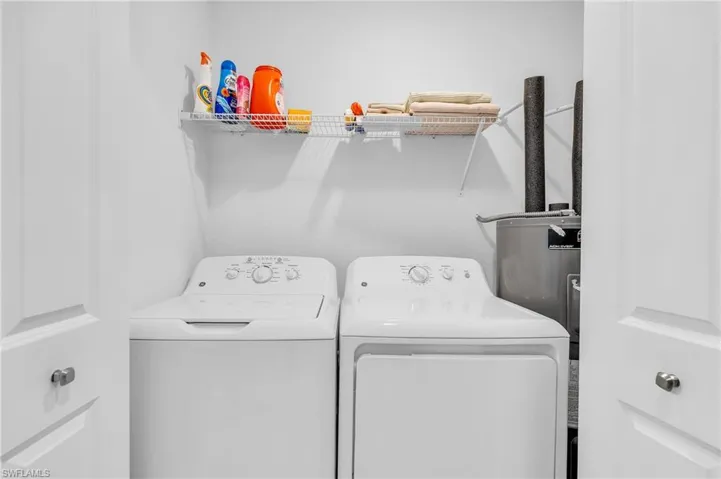 Clothes washing area featuring washing machine and clothes dryer and water heater