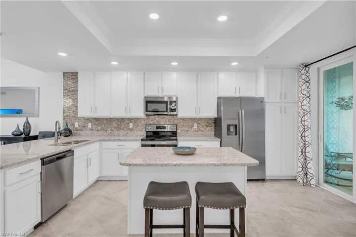 Kitchen featuring appliances with stainless steel finishes, crown molding, a breakfast bar, sink, and light stone counters