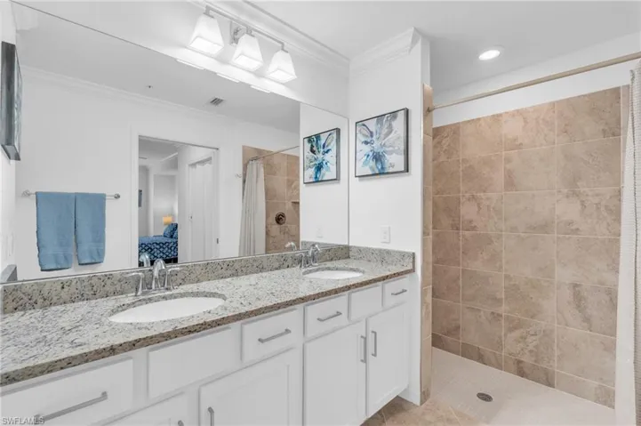 Bathroom featuring tile patterned flooring, walk in shower, crown molding, and vanity