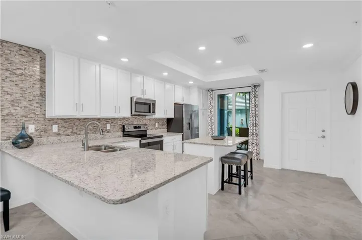 Kitchen featuring a breakfast bar area, appliances with stainless steel finishes, kitchen peninsula, sink, and white cabinetry