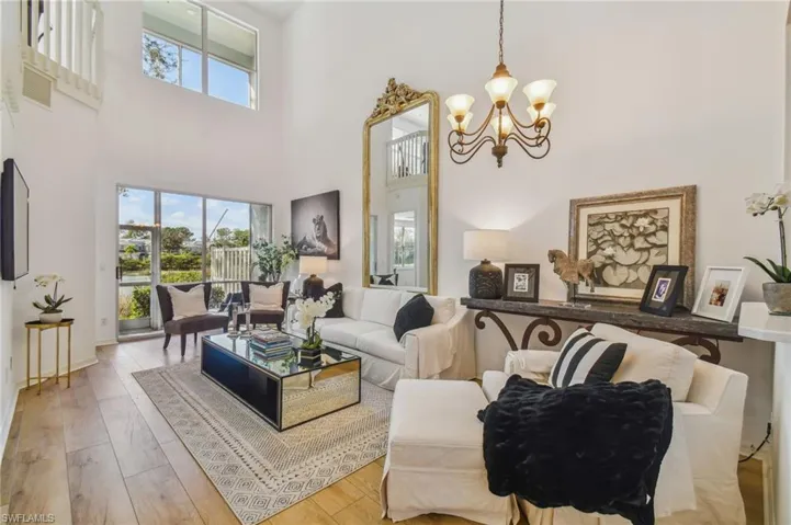 Living room with a high ceiling, an inviting chandelier, and light hardwood / wood-style flooring