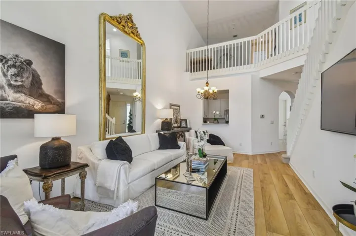 Living room with high vaulted ceiling, light hardwood / wood-style floors, and a chandelier