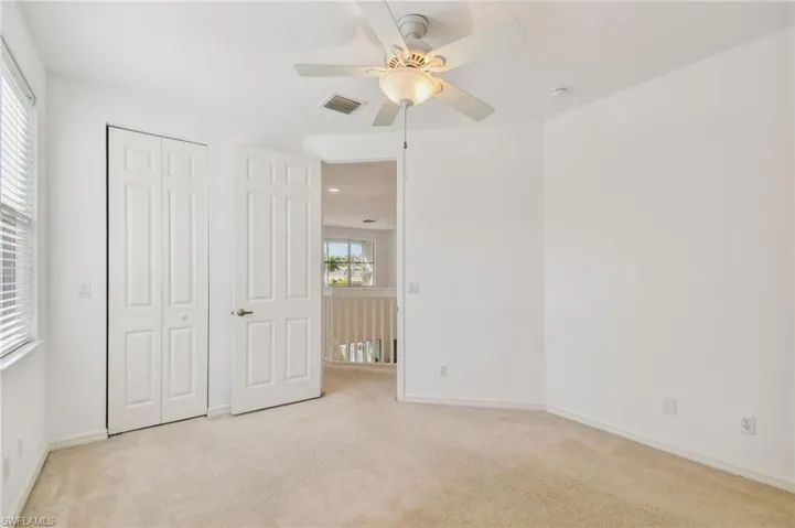 Unfurnished bedroom featuring light carpet, ceiling fan, and a closet