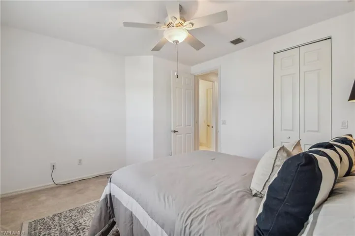 Bedroom with a closet, ceiling fan, and light colored carpet